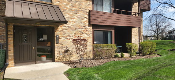 Front view of a brick building with a brown door and a large window.