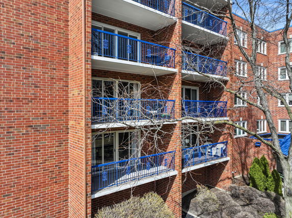 Front view of a multi-story brick building with blue railings on balconies.