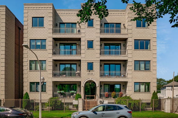 Front view of a multi-story building with balconies and large windows.