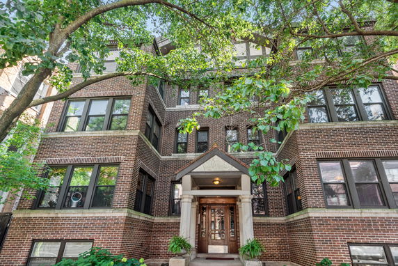 Front view of a multi-story brick apartment building with a central entrance.