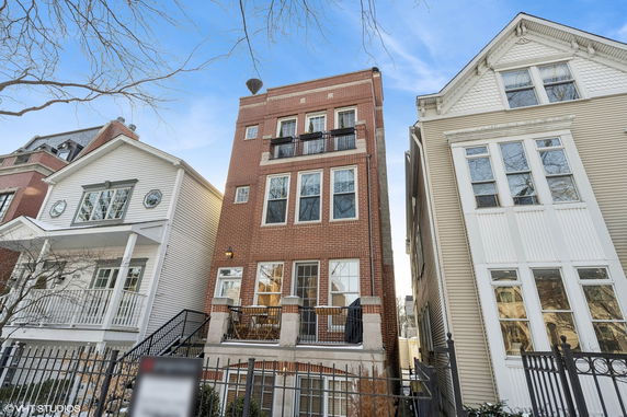Front view of a multi-story brick house with balconies.