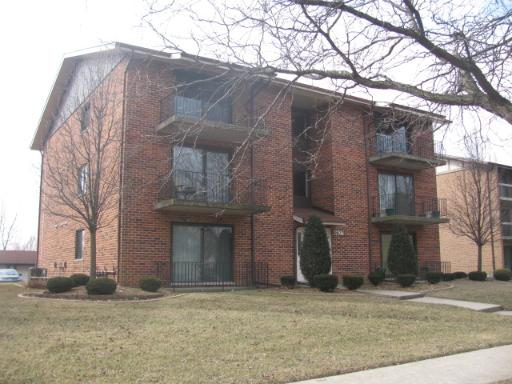 Front view of a three-story brick apartment building with balconies.