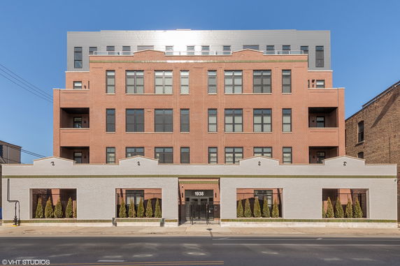 Front view of a multi-story brick building with large windows.