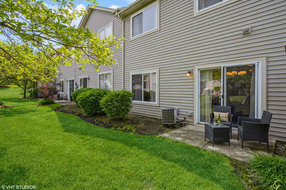 Side view of a two-story house with a patio and sliding glass doors.