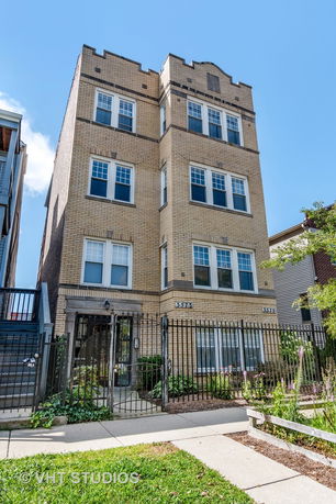 Front view of a multi-story brick building with a gated entrance.