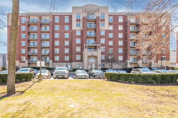 Front view of a multi-story brick apartment building with balconies.