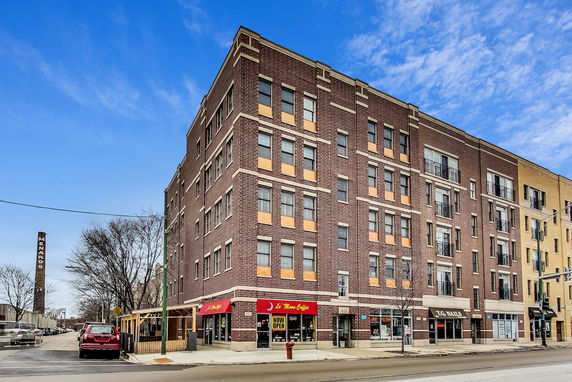 Front view of a multi-story brick building with retail shops on the ground floor.