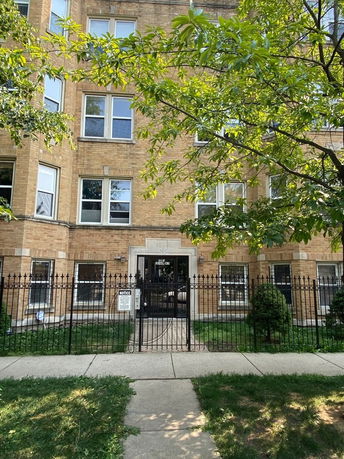 Front view of a multi-story brick building with a gated entrance.