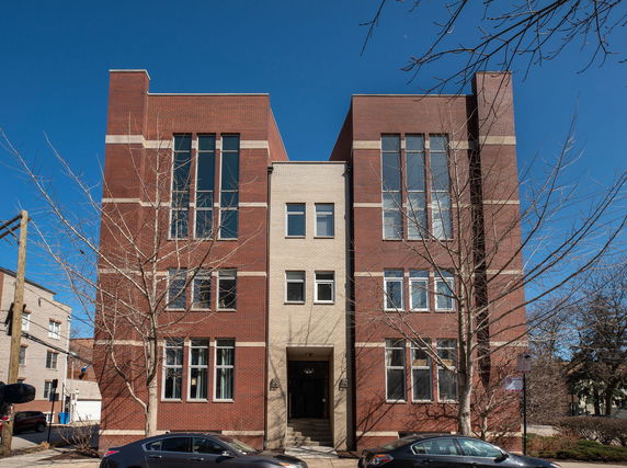 Front view of a three-story brick apartment building with tall windows.