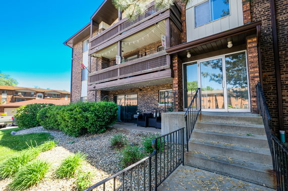 Front view of a multi-story apartment building with balconies and a glass entrance door.