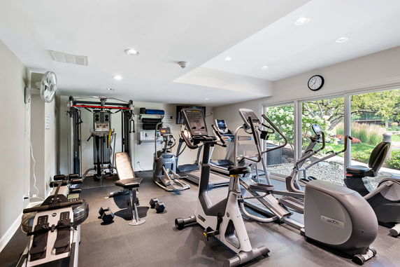 Indoor gym area with exercise equipment and large windows.