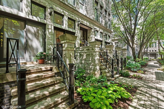 Front view of a stone townhouse with stairs leading to the entrance.