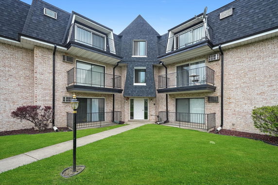 Front view of a multi-story building with balconies and brick exterior.