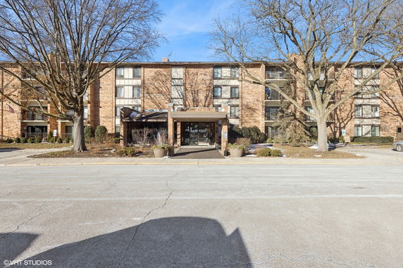 Front view of a multi-story brick apartment building with balconies.