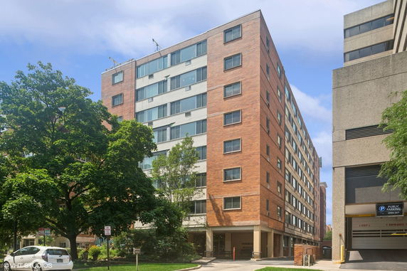 Front view of a multi-story apartment building with brick facade and large windows.