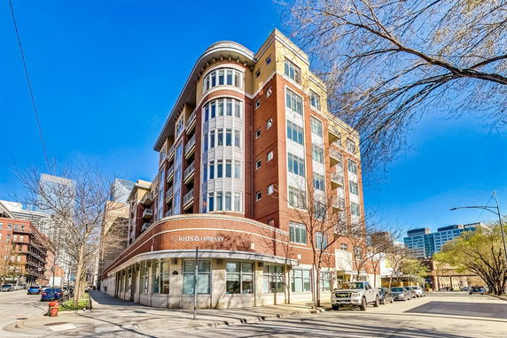 Front view of a multi-story brick and glass building on a street corner.