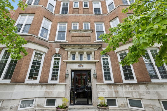 Front view of a multi-story brick building with tall windows and decorative detailing around the entrance.
