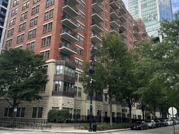 Front view of a multi-story apartment building with balconies and brick facade.
