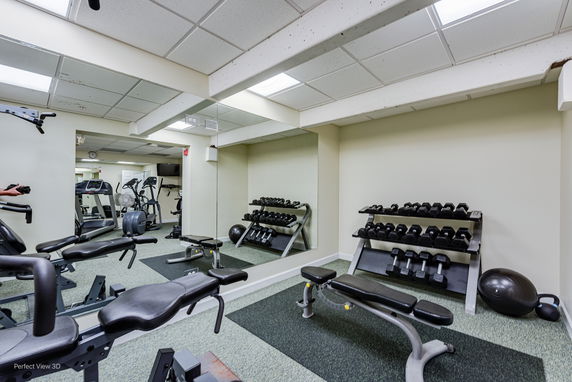 Interior view of a gym area with exercise equipment and weights.