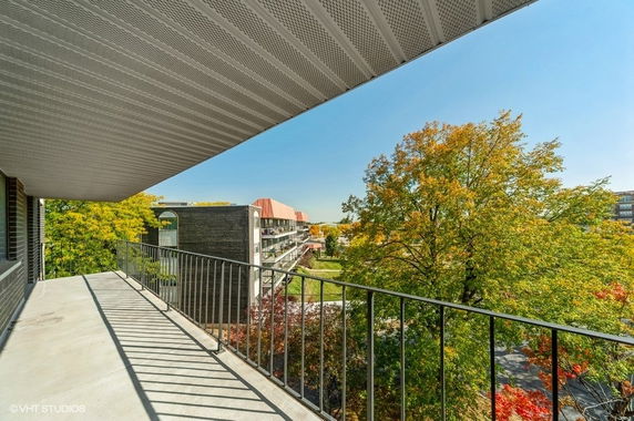 Balcony view showing surrounding buildings and trees.