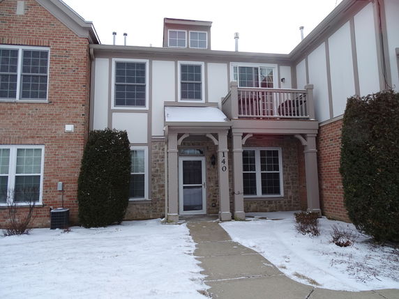 Front view of a two-story townhouse with a small balcony over the entrance.