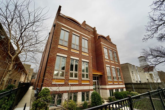 Front view of a brick multi-story building with multiple windows.