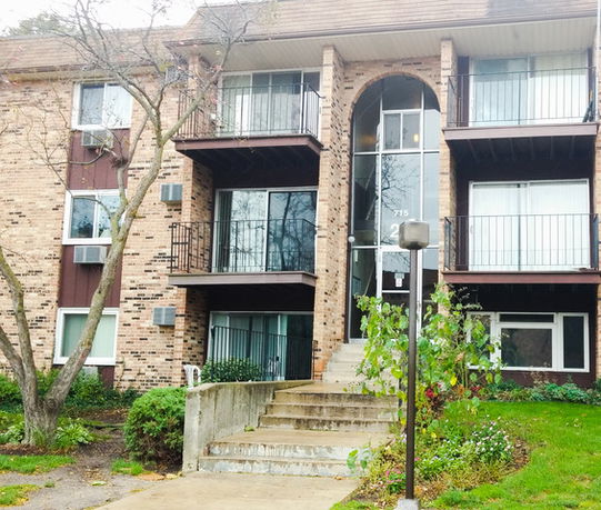 Front view of a multi-story brick apartment building with balconies.