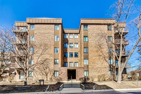 Front view of a multi-story brick apartment building with balconies.
