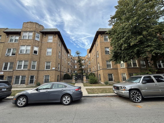 Front view of a multi-story brick apartment building with multiple windows.