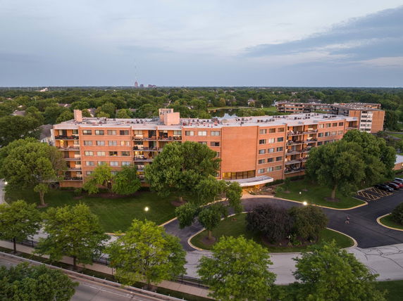 Front view of a large multi-story apartment building surrounded by trees.