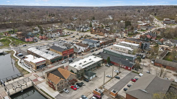 Aerial view of a small town with a mix of commercial buildings, residential houses, and a nearby river.