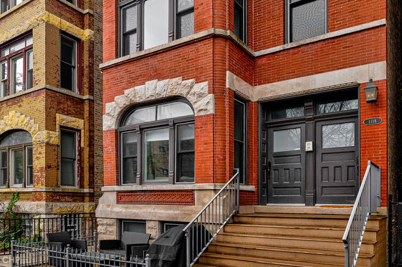 Front view of a multi-story brick building with steps leading to a double door entrance.