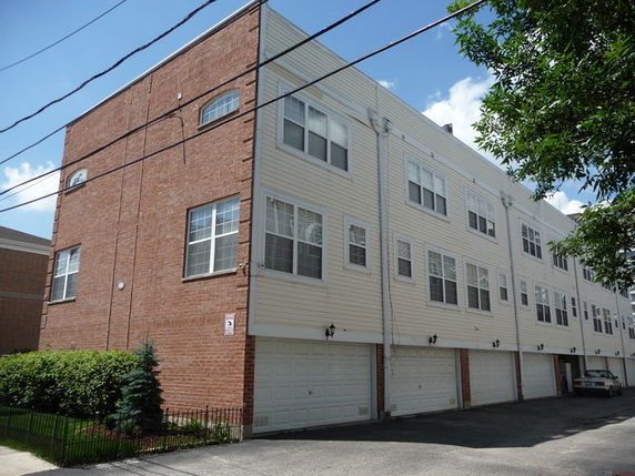 Front view of a multi-story residential building with garages on the ground level.