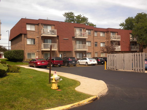 Front view of a three-story brick apartment building with balconies.