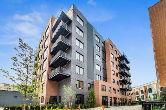 Front view of a modern multi-story apartment building with balconies.