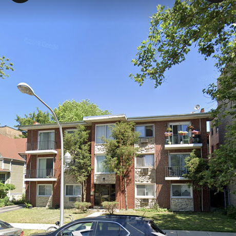 Front view of a multi-story residential building with balconies and a brick facade.