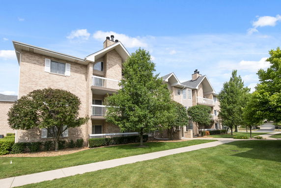 Front view of a multi-story apartment building with brick exterior and balconies.