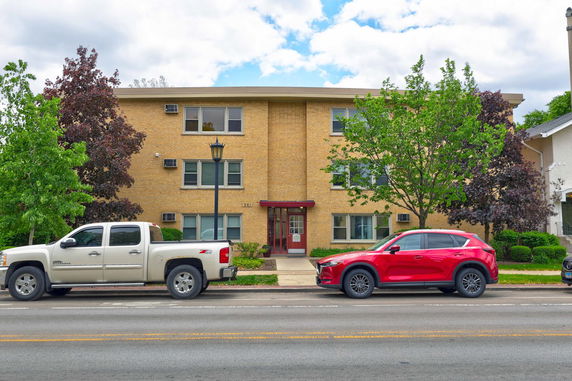 Front view of a three-story brick apartment building with a flat roof.