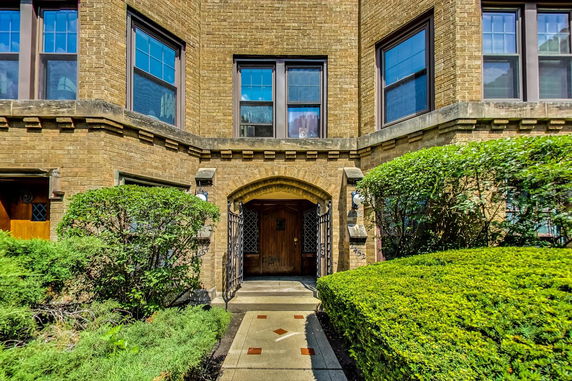 Front view of a brick building entrance with arched doorway and windows.