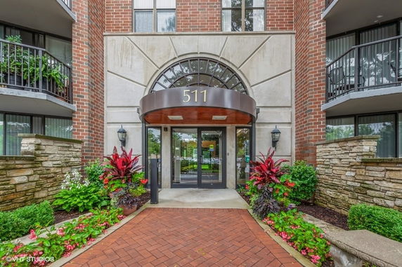 Front view of a brick building entrance with a decorative awning and landscaped area.