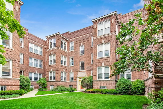 Front view of a multi-story brick apartment building with multiple windows.
