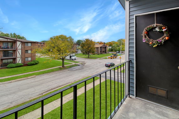 View from a building balcony overlooking residential street and nearby buildings.