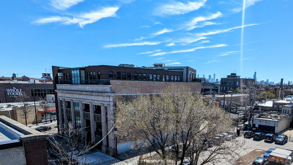 View of a multi-story brick building with urban surroundings and distant skyscrapers.