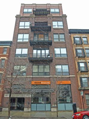 Front view of a multi-story brick building with large windows and balconies.