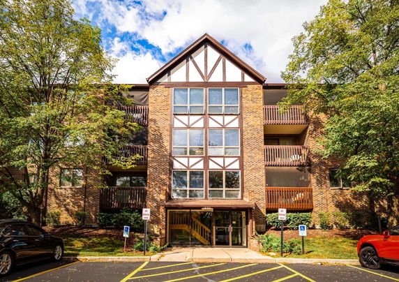 Front view of a multi-story brick apartment building with wooden balconies.