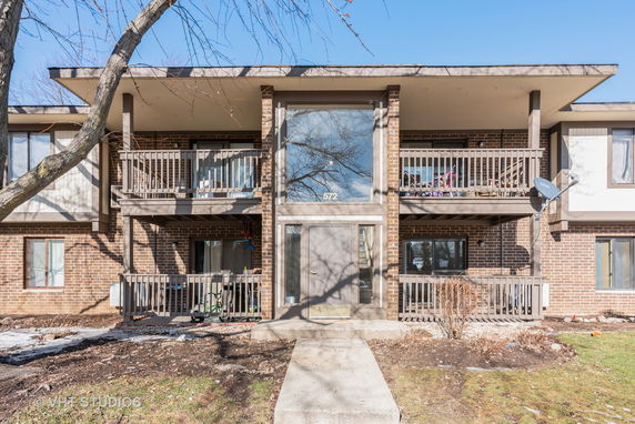 Front view of a multi-story brick apartment building with balconies.