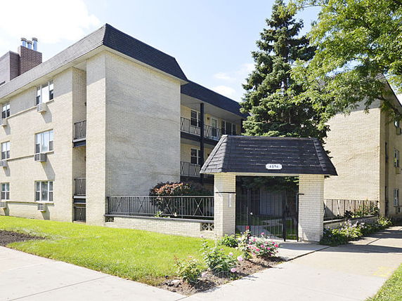 Front view of a multi-story apartment building with a gated entrance.