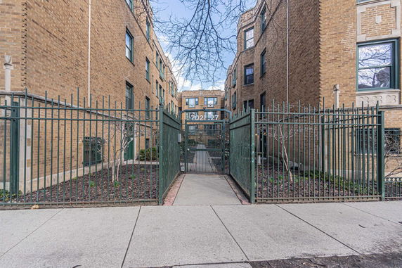 Front view of a multi-story brick building with gated entrance.