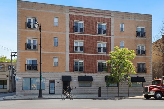Front view of a multi-story brick building with small balconies.