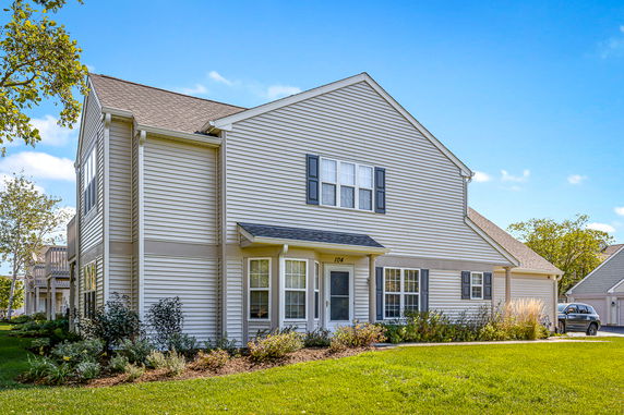 Front view of a two-story house with beige siding and black shutters.
